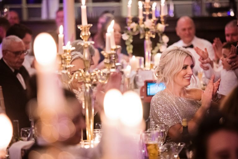 Atmospheric candid photo of wedding guest clapping at wedding speeches.