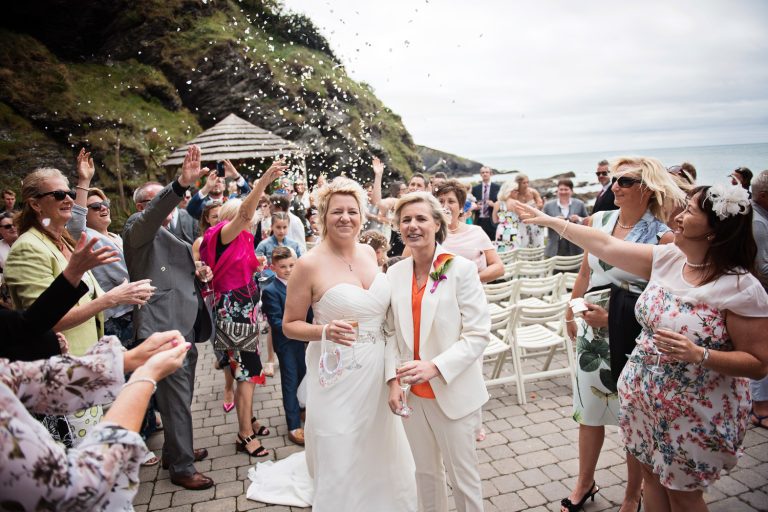 Relaxed, candid photo of wedding guests throwing confetti over the bride and bride.