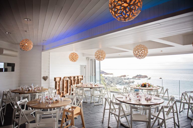 Wedding breakfast laid out at Tunnel Beach. The doors are also open, and lead you out to a impressive view of the Devon coastline.