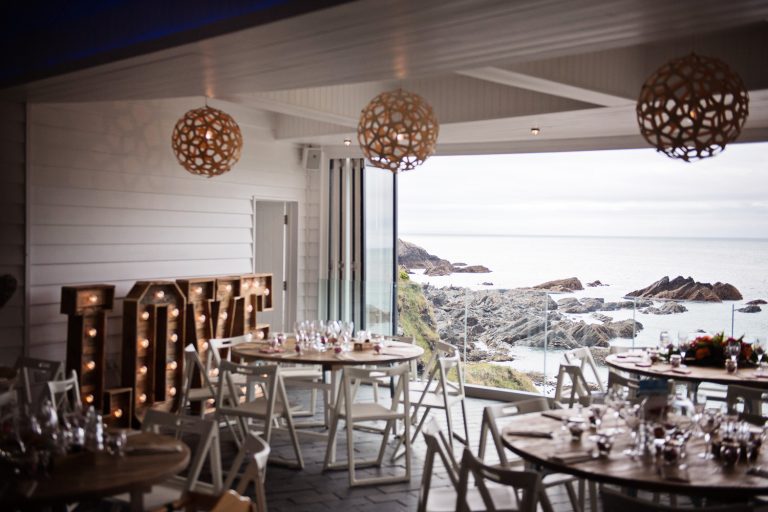 Wedding breakfast laid out at Tunnel Beach. The doors are also open, and lead you out to a impressive view of the Devon coastline.