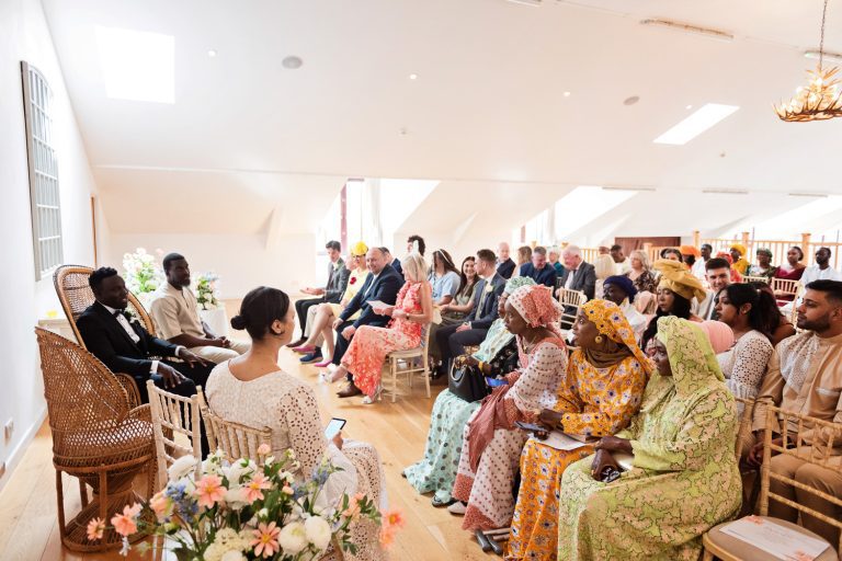 Groom and wedding guests (dressed in African attire), wait for the bride to arrive.