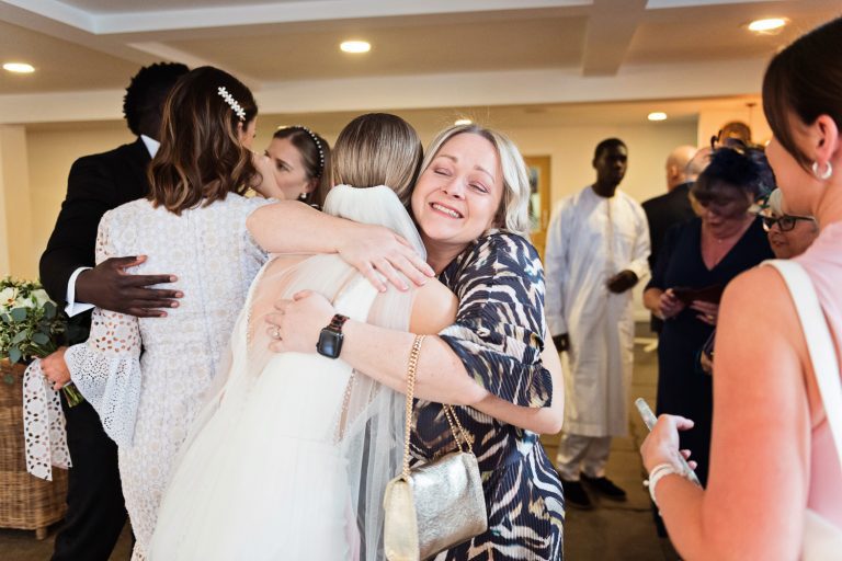 Natural candid photo of bride being hugged by her wedding guests.