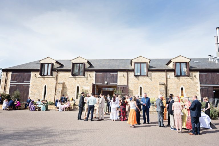 Worton Hall with wedding guests naturally mingling in the outdoor courtyard.