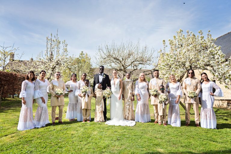 Bridal party standing on the lawn in front of flowering trees.