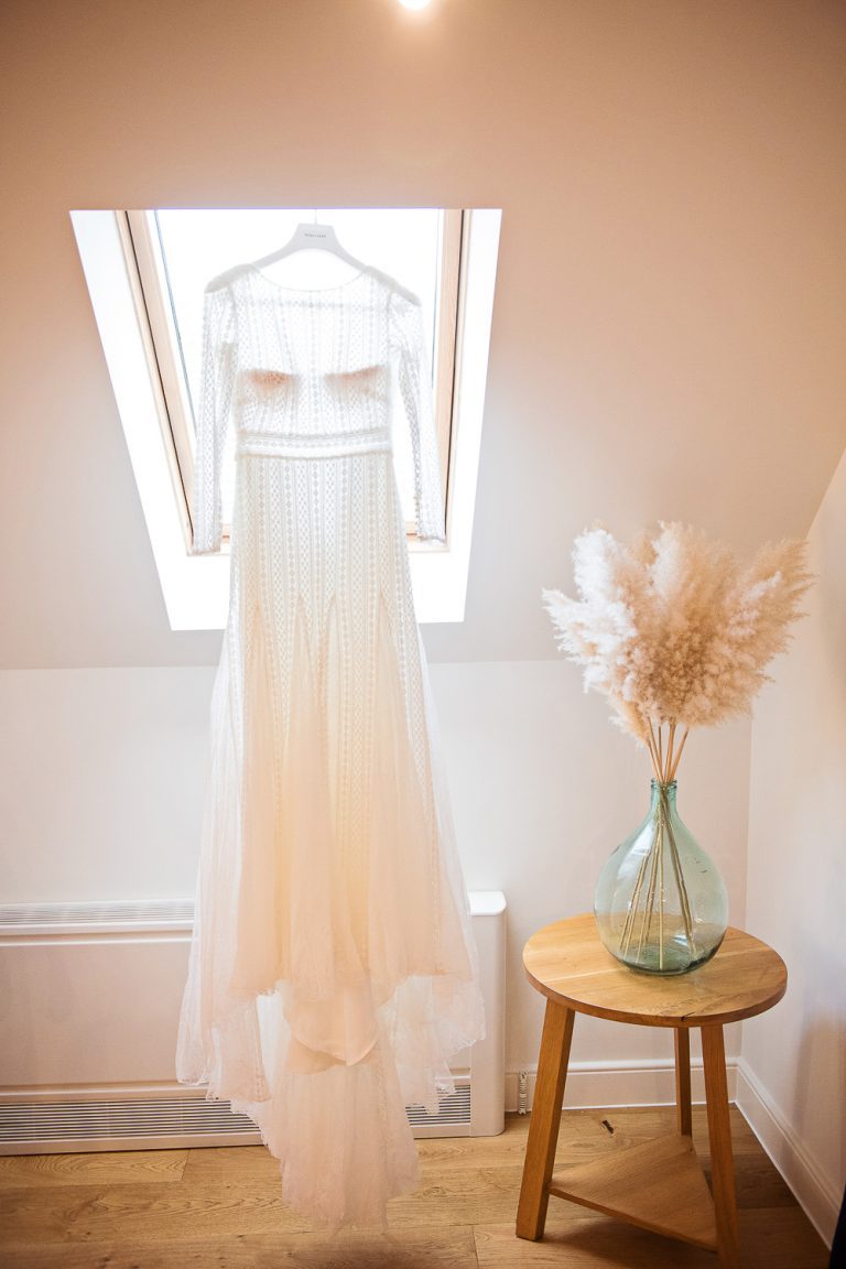 Portrait photo of the wedding dress being hung up.