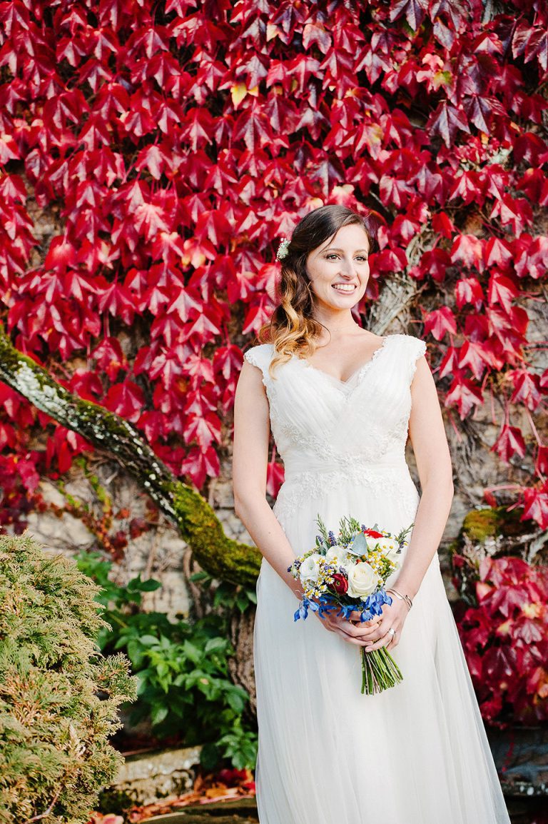 Portrait of the bride with red leaves behind her. Striking photo.