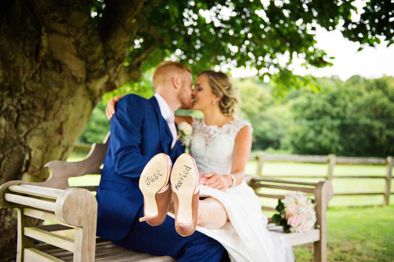 "Just married" written on the under sole of brides shoes as the bride kisses the groom.