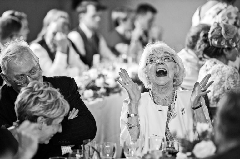 B&W candid wedding photo of gran laughing her head off.
