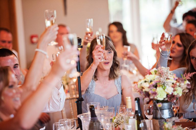 Storytelling photo of wedding party raising a glass for the end of speeches.