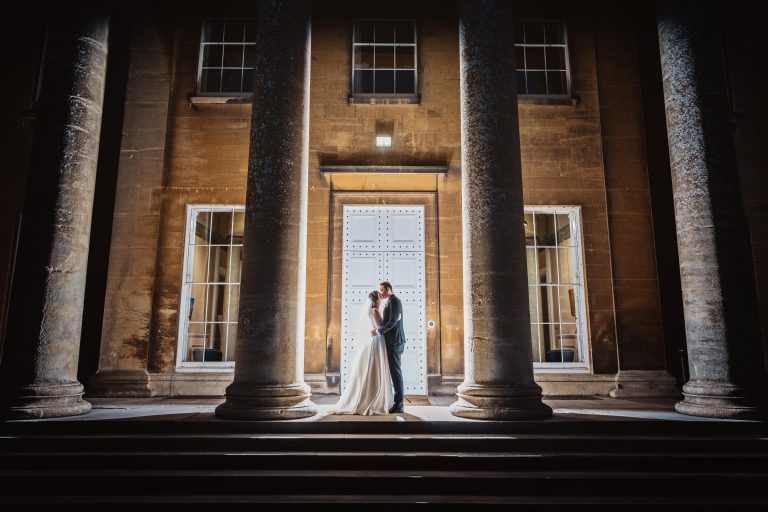 Exterior night time shot of bride and groom lit up by off camera flash at the top of the stairs outside at Leigh Court.