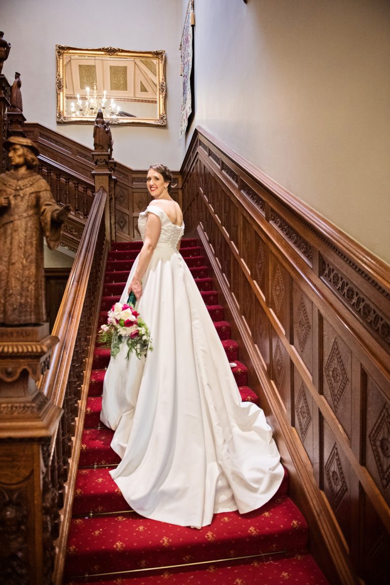 Portrait photo of the bride and her long dress down the stairs at Manor By The Lake.