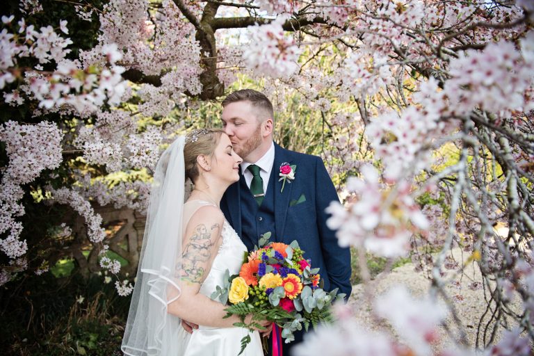 Bride and groom stand in a blossoming tree and grab a moment to themselves.