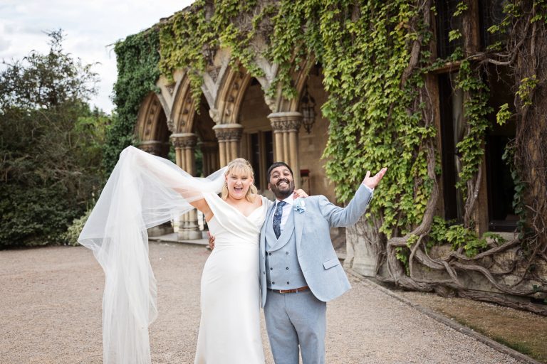 Bride and groom raise their arms in the air and look very happy.