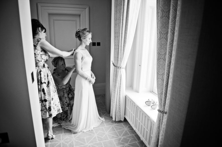 B&W photo of the bride getting into her wedding dress.