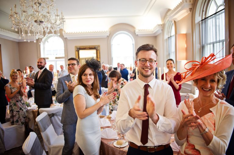 Wedding guests cheer at the bride and groom.