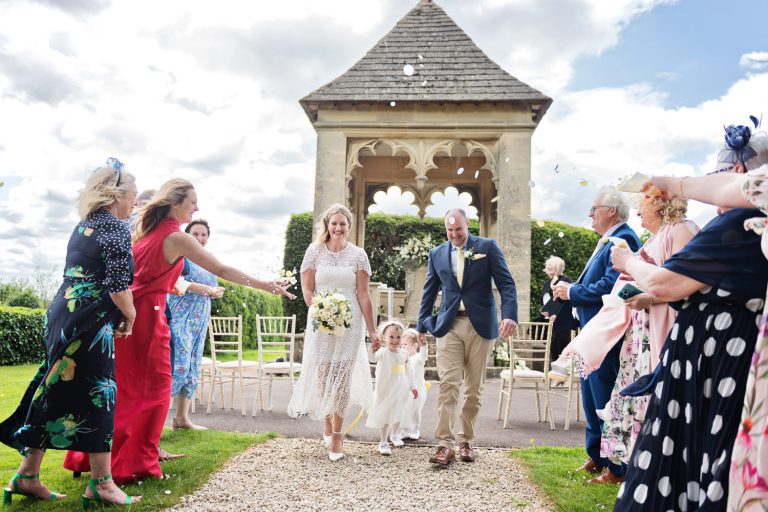 Bride and groom walk hand in hand with their children after their outdoor wedding ceremony at Ellenborough Park.