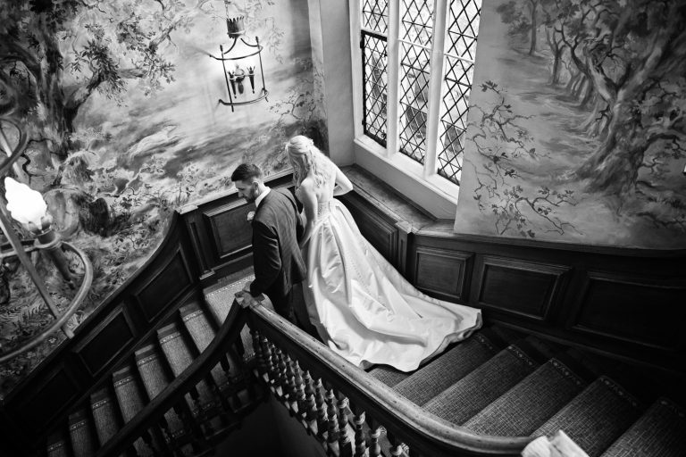 B&W photo of bride and groom walking down the magnificent staircase at Ellenborough Park.