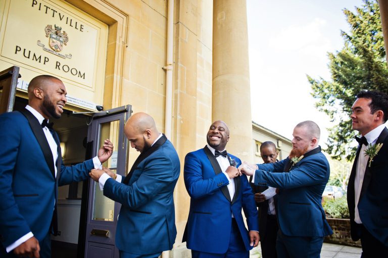 Groomsmen getting ready outside the side entrance of Pittville Pump Room. You can see the Pittville Pump Rooms.