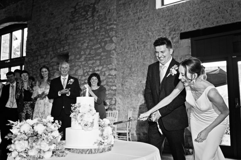 Bride and groom cut the wedding cake at Priston Mill.