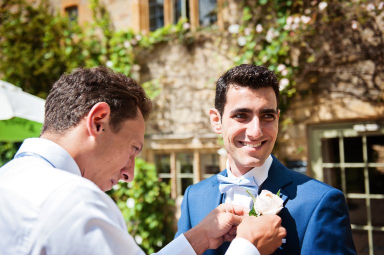 Candid photo of the groom having his button hole put on at The Slaughters Country Inn