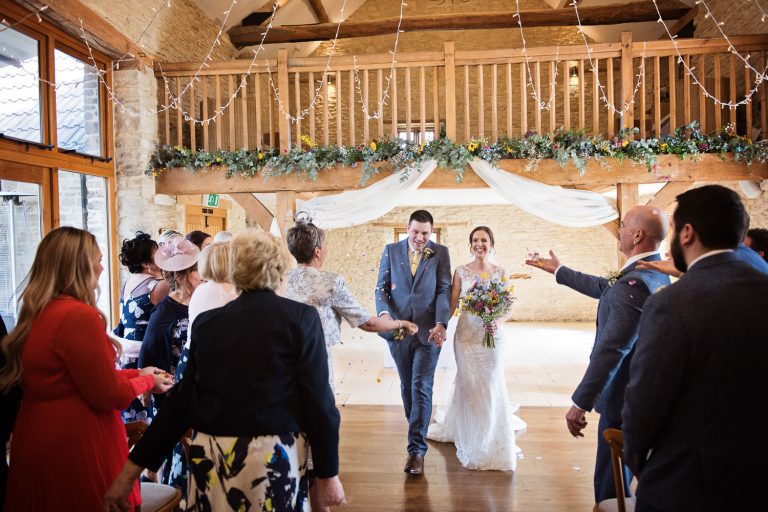 Candid photo of Bride and groom exit the wedding barn after their wedding ceremony.