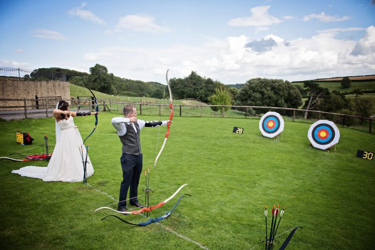 Bride and groom playing archery in the grounds
