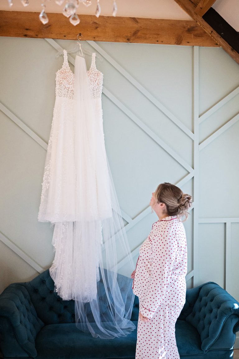 Bride looking at her wedding dress hung up.