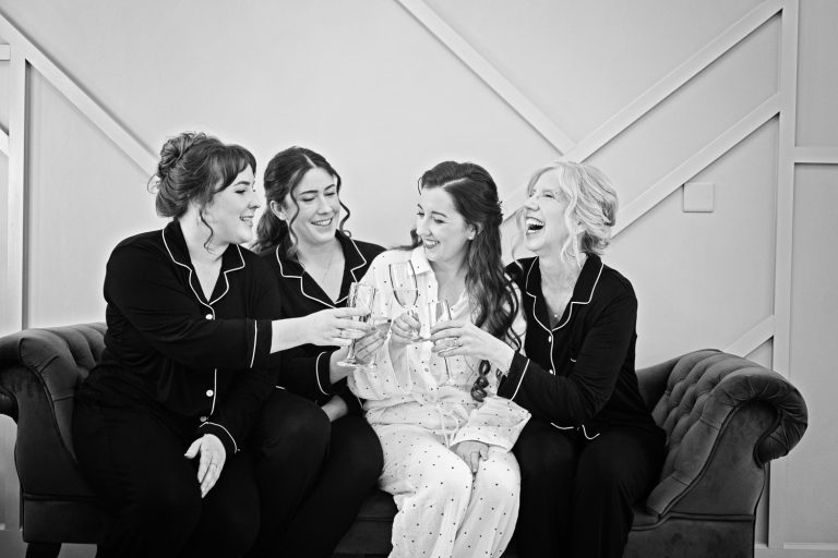Bride and bridesmaids and mum laughing together at Kingscote Barn.