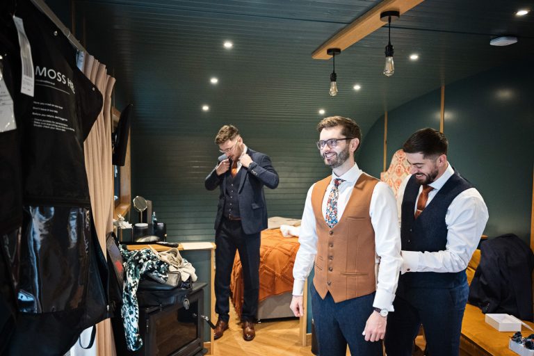 Groomsmen get ready for a wedding inside the accommodation at Kingscote Barn.