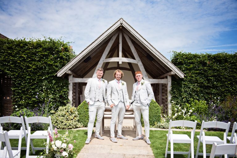 Groomsmen stand in front of Linhay at Kingscote Barn.