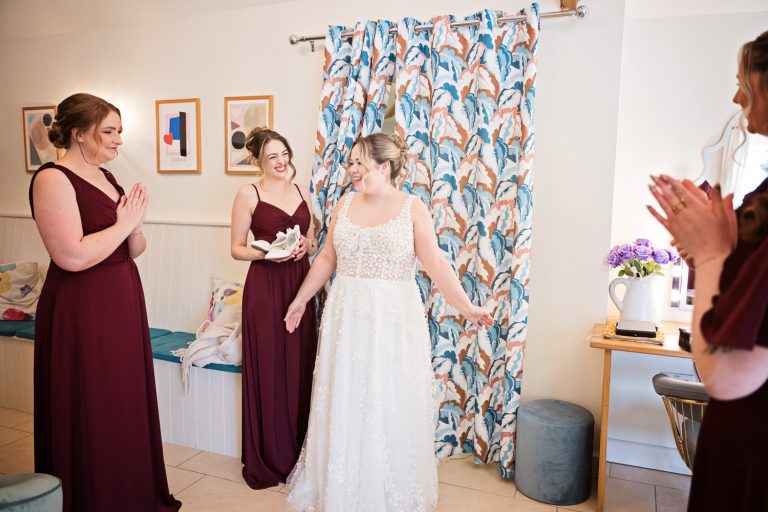 Bride steps out to applause from her bridesmaids.