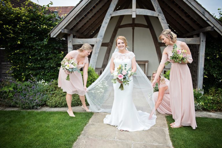 Bridesmaids tend to the brides wedding dress.