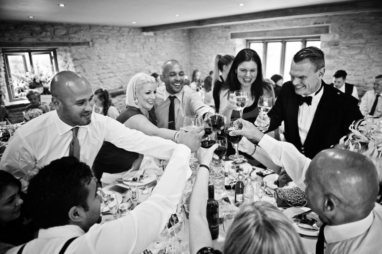 Candid pic of wedding guests cheer each other with their glasses