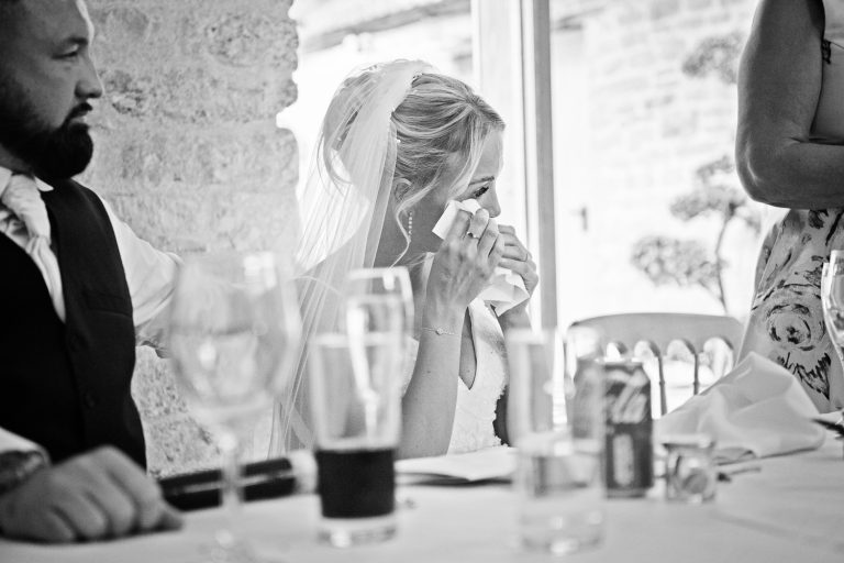 Bride wiping her eye during an emotional speech at Kingscote Barn.