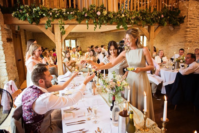 Candid photo Bridesmaids dishing out the shots during speeches at Kingscote Barn.