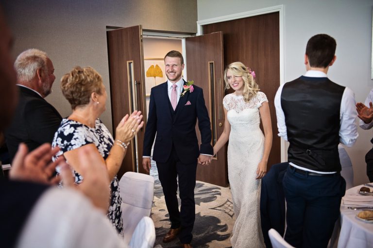 Bride and groom enter the Cotswold Suite at their wedding at Tewkesbury Park.