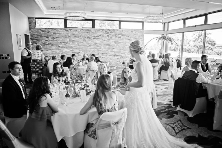 Documentary photo of bride chatting to wedding guests at Tewkesbury Park in the Cotswold Suite.