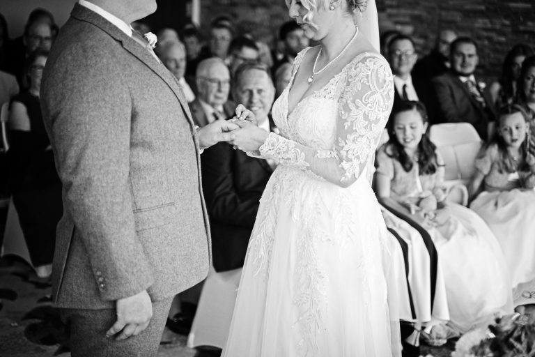 Candid moment of bride and groom exchanging wedding rings at Tewkesbury Park