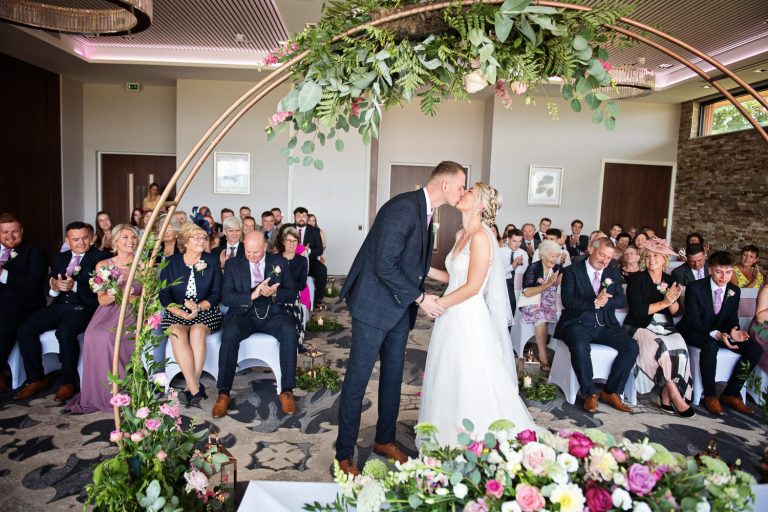 Candid moment of bride and groom getting married kissing during the ceremony at Tewkesbury Park