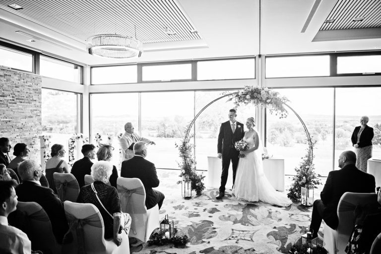 B&W photo of a wedding taking place in the Cotswold Suite at Tewkesbury Park