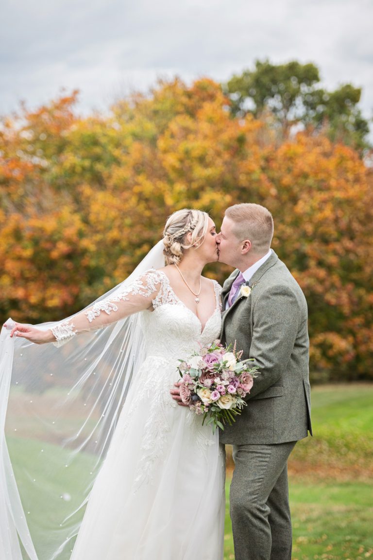 Autumnal tree's behind Bride and groom as they grab a moment in the grounds at Tewkesbury Park.