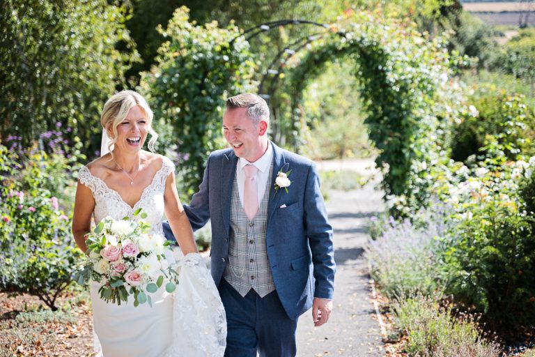Candid moment of Bride and groom laughing in the gorgeous gardens at Tewkesbury Park.