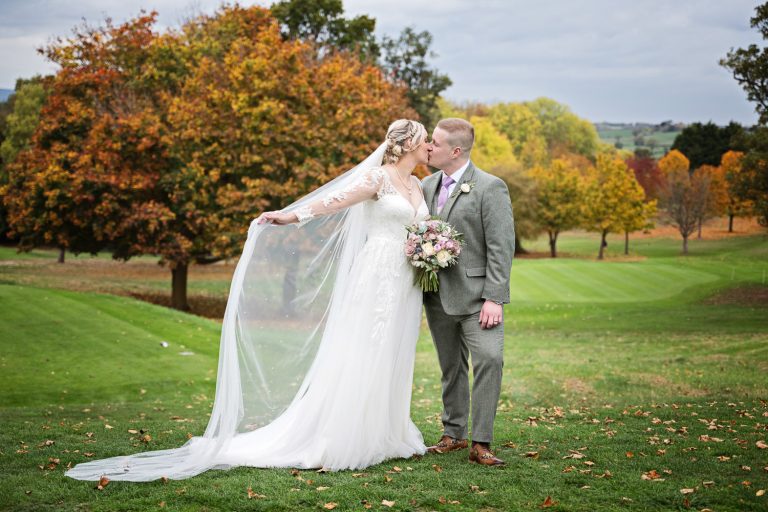Bride and groom grab a moment in the grounds at Tewkesbury Park. Autumnal tree's behind them.