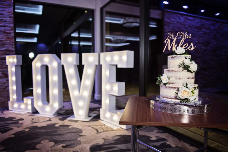 Love letters lit up and a wedding cake in the Cotswold Suite at Tewkesbury Park