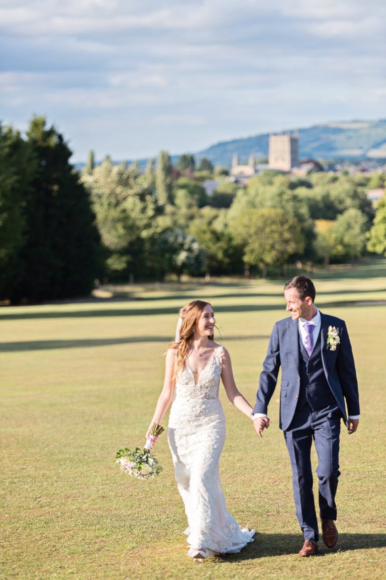Bride and groom grab a moment in the gorgeous grounds at Tewkesbury Park with Tewkesbury Abbey in the background.
