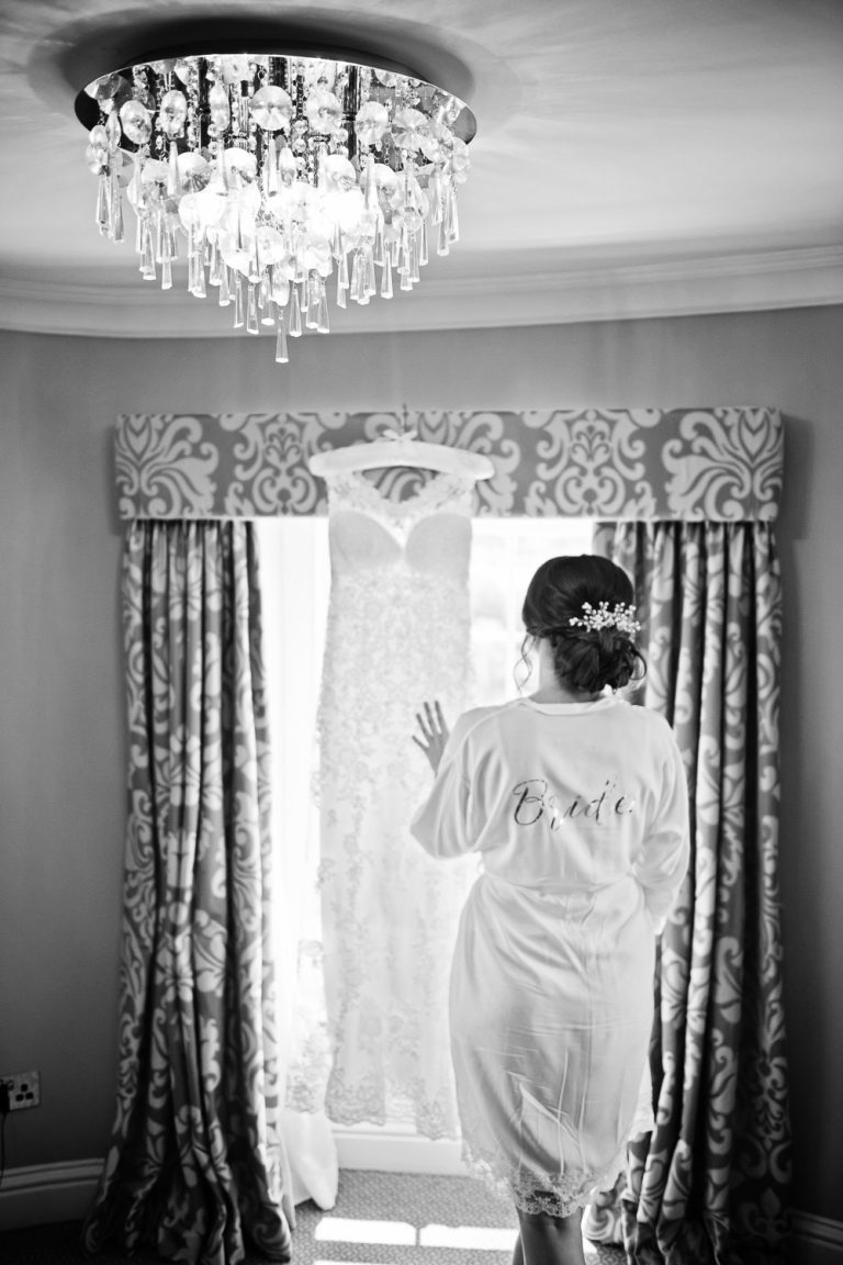 B&W documentary photo of a bride looking at her wedding dress.