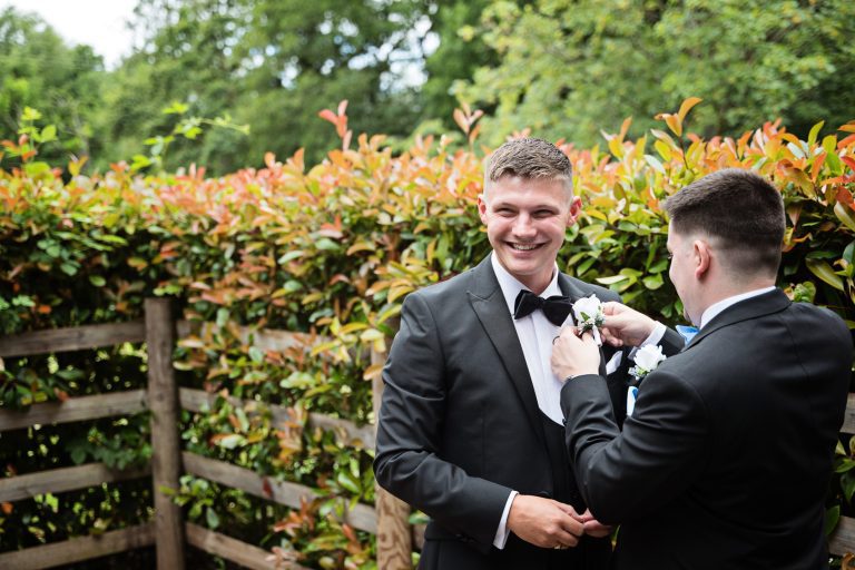 Candid photo of the bestman adding the grooms button hole flower.