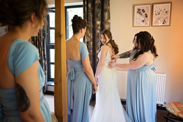 Bridal party help do the brides dress at The Mill Barns.