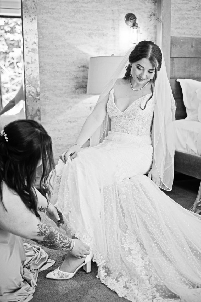 Portrait photo of bridesmaid putting on the brides wedding shoes.