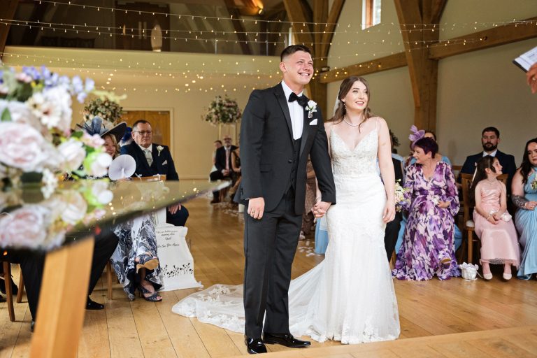 Bride and groom stand in front of their wedding guests during their wedding ceremony at The Mill Barns.